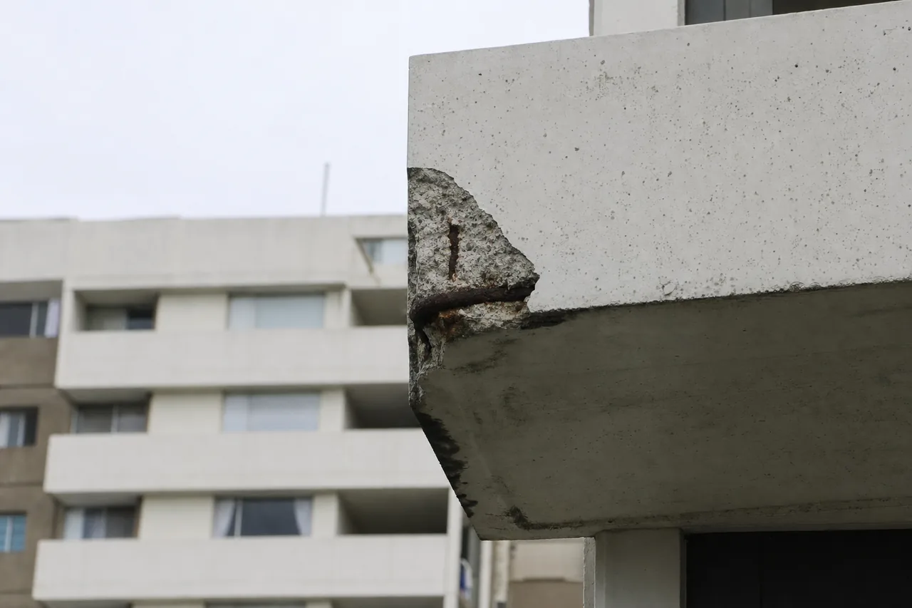 A balcony slab edge with a patch of concrete broken away and a rusted bar showing — concrete cancer repair, Newcastle. Illustrative example.